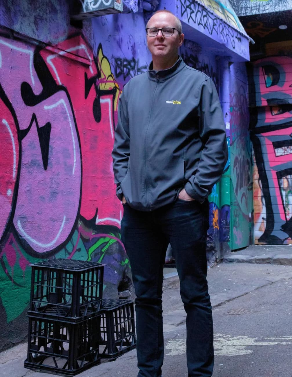 A local MailPlus owner-operator standing in a Melbourne laneway in branded uniform